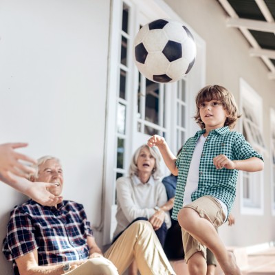 Private Haftpflichtversicherung: Familien schaut einem Kind beim Fussball jonglieren zu