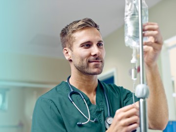 Grundfähigkeitsversicherung: Pfleger hantiert mit einem Tropf
