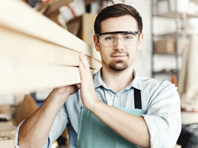 Schreiner trägt Holzbalken