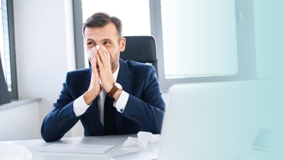 Arbeiten trotz Krankschreibung: Mann putzt sich die Nase