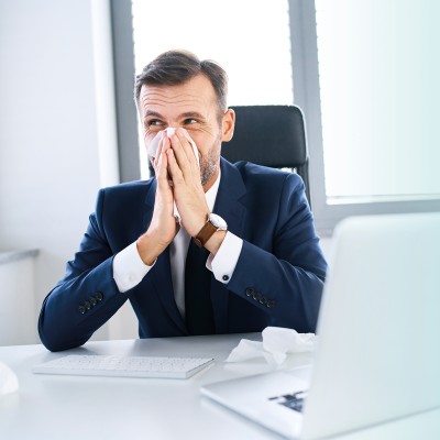 Arbeiten trotz Krankschreibung: Mann putzt sich die Nase