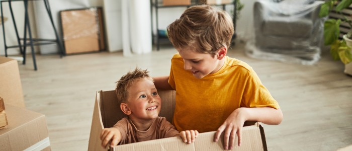Zwei Kinder spielen mit einem Karton