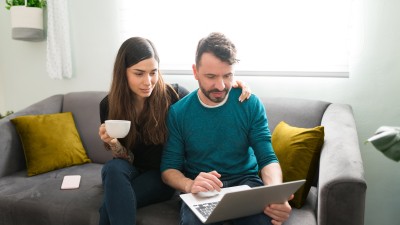 Paar auf dem Sofa schauen gemeinsam in den Laptop