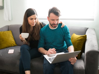 Paar auf dem Sofa schauen gemeinsam in den Laptop