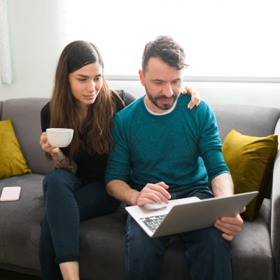 Paar auf dem Sofa schauen gemeinsam in den Laptop