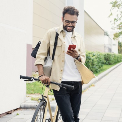 Mann schiebt sein Fahrrad und schaut auf sein Smartphone