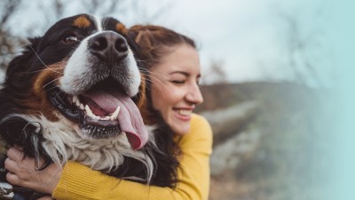 Tierhalterhaftpflicht: Junge Frau umarmt glücklich ihren Hund