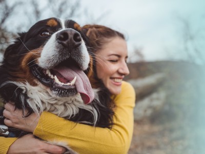 Tierhalterhaftpflicht: Junge Frau umarmt glücklich ihren Hund