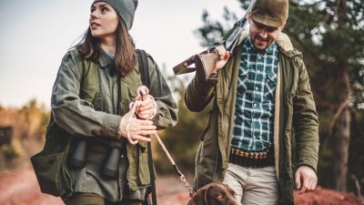 Jagdhaftpflichtversicherung: Junge Frau und Mann laufen mit ihrem Hund im Wald