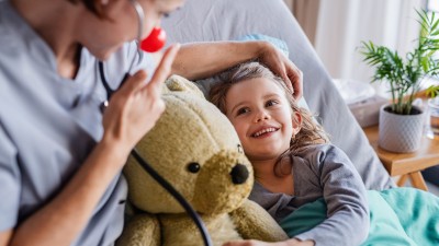 Krankenzusatzversicherung für Ihr Kind: Kleines Mädchen liegt im Bett mit einem Teddybär