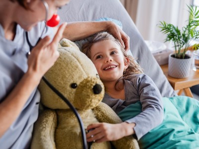 Krankenzusatzversicherung für Ihr Kind: Kleines Mädchen liegt im Bett mit einem Teddybär