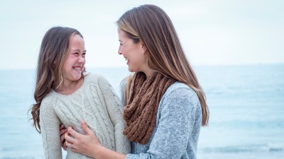 Mutter hält ihre Tochter im Arm - im Hintergrund Wasser
