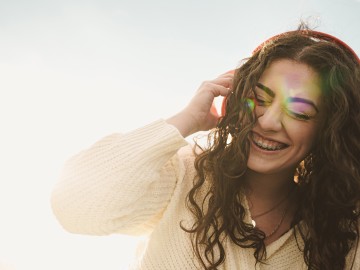 Eine Frau mit Zahnspange telefoniert und lacht dabei