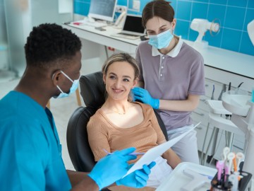 Ein Zahnarzt erklärt einer Patientin im Behandlungsstuhl etwas.