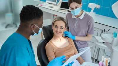 Ein Zahnarzt erklärt einer Patientin im Behandlungsstuhl etwas.