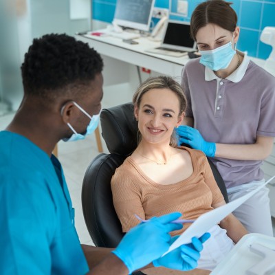 Ein Zahnarzt erklärt einer Patientin im Behandlungsstuhl etwas.