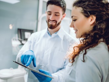 Zahnarzt zeigt einer Patientin den Befund auf einem Tablet