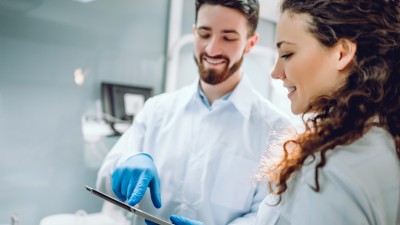 Zahnarzt zeigt einer Patientin den Befund auf einem Tablet