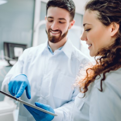 Zahnarzt zeigt einer Patientin den Befund auf einem Tablet