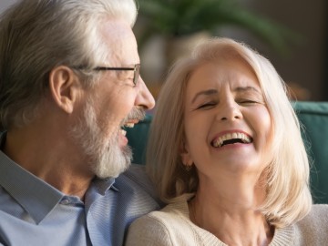 Glückliches älteres Paar lachend auf dem Sofa