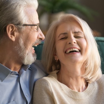 Glückliches älteres Paar lachend auf dem Sofa