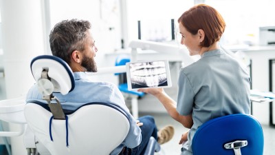 Die Zahn&auml;rztin zeigt dem Patienten ein R&ouml;ntgenbild auf dem Tablet