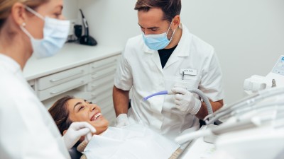 Eine Patientin sitzt lächelnd im Behandlungsstuhl beim Zahnarzt