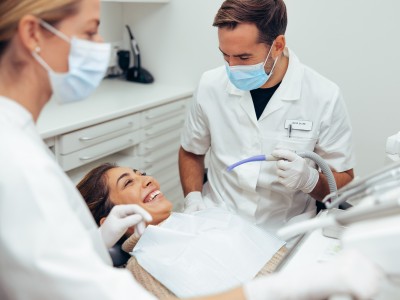 Eine Patientin sitzt lächelnd im Behandlungsstuhl beim Zahnarzt