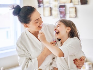 Mutter und Tochter putzen sich gegenseitig die Zähne