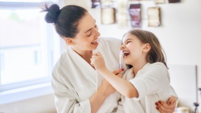 Mutter und Tochter putzen sich gegenseitig die Zähne