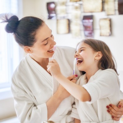 Mutter und Tochter putzen sich gegenseitig die Zähne