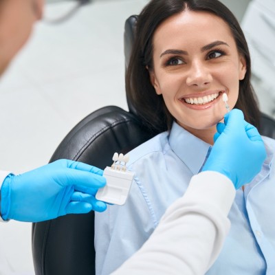 Zahnarzt gleicht Veneers an einer Patientin ab