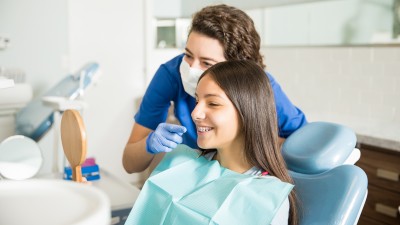 Keramikbrackets - Arten, Kosten & Erstattung: Zahnärztin erklärt einer Patientin die Zahnspange