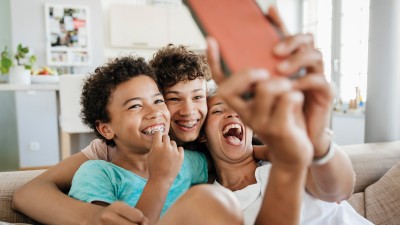 Kinder mit Zahnspangen albern mit einem Smartphone herum