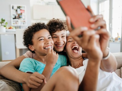 Kinder mit Zahnspangen albern mit einem Smartphone herum