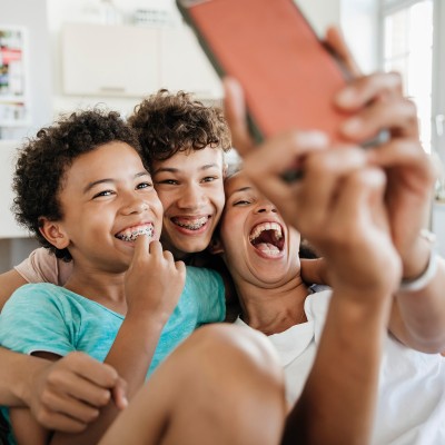 Kinder mit Zahnspangen albern mit einem Smartphone herum