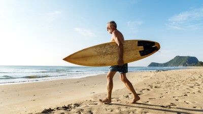 Senior mit dem Surfbrett am Strand