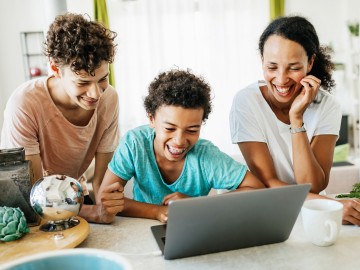 Jugendliche lachend vor einem Laptop