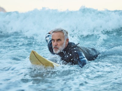 Senior auf einem Surfboard in den Wellen