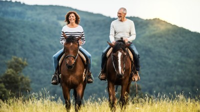 Paar mit zwei Pferden in der Natur unterwegs