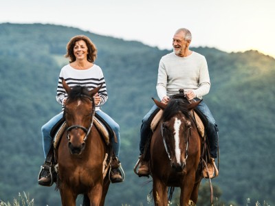 Paar mit zwei Pferden in der Natur unterwegs