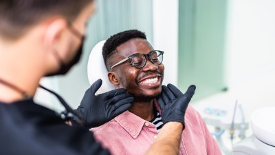 Zahnzusatzversicherung für die Zahnreinigung: Patient lächelnd auf dem Behandlungsstuhl einer Zahnarztpraxis 