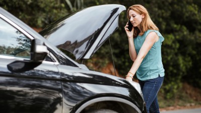 Mobilitätsschutz-Versicherung: Frau mit Autopanne ruft mit Smartphone Hilfe