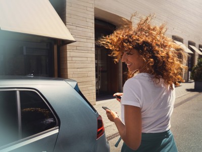 Kfz-Versicherung: Junge Frau mit Autoschlüsse an Ihrem Fahrzeug
