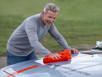 Ein Mann poliert die Motorhaube seines Oldtimers