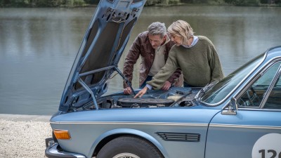 Ein Mann und eine Frau schauen in einen geöffneten Motorraum eines BMW-Oldtimers