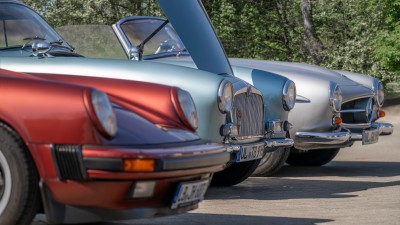 Drei Oldtimer auf einem Parkplatz