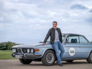 Oldtimer-Versicherung:  Mann lehnt an einem BMW-Oldtimer Klassiker