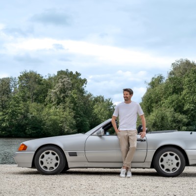 Youngtimer-Versicherung: Mann steht lässig vor seinem Mercedes-Youngtimer