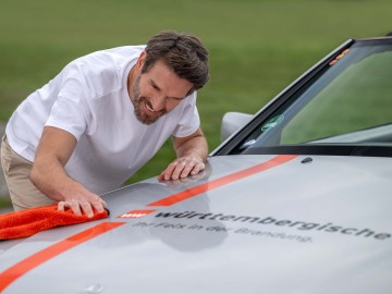 Mann poliert die Motorhaube seines Youngtimers